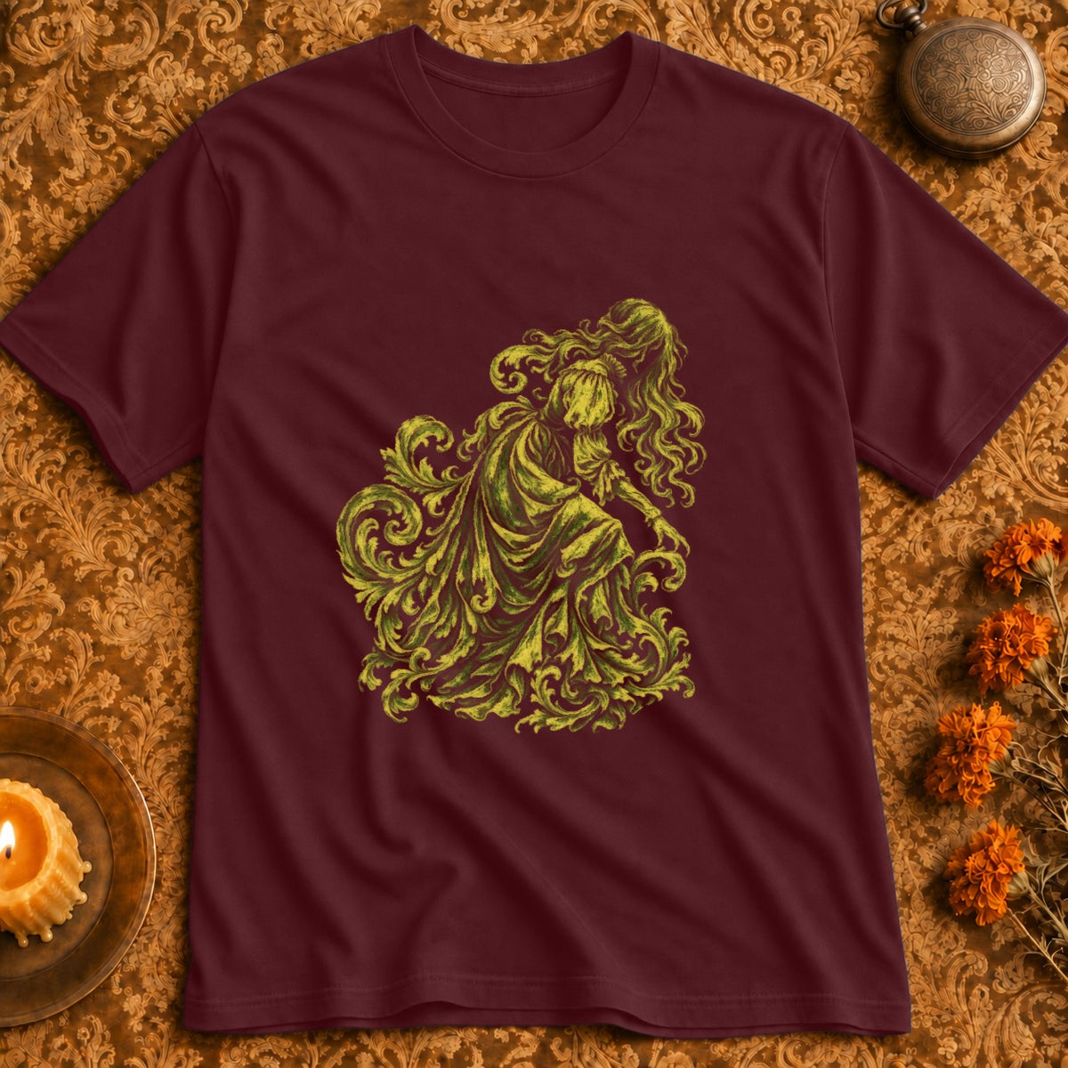 Maroon t-shirt with a yellow-green illustration of a flowing figure amidst ornate foliage.