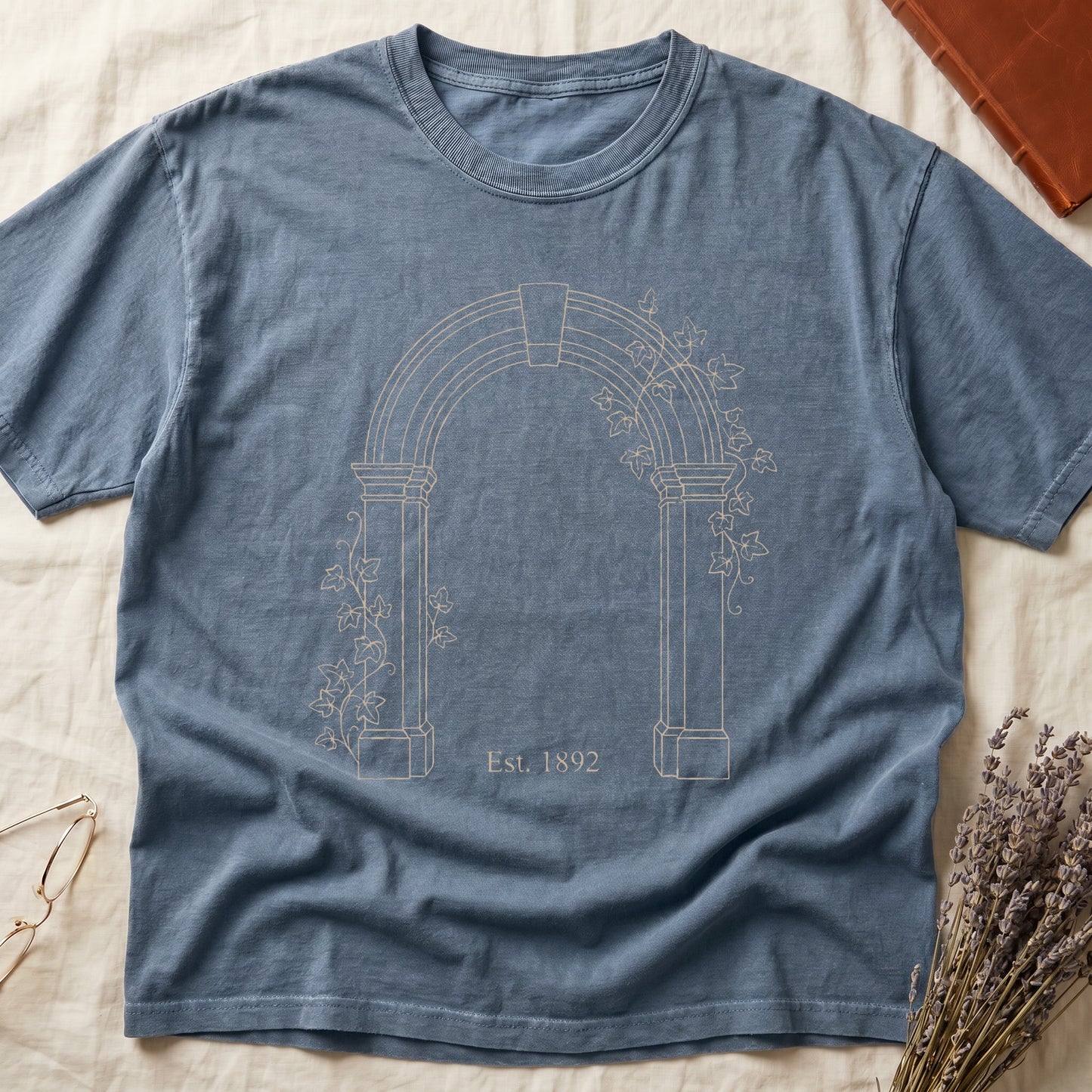 Blue Jean tee with Gothic stone archway in cream linework, ivy climbing the columns, "Est. 1892" inscribed at the base.