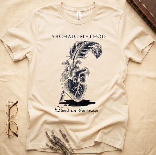 Natural tee with anatomical heart and quill emerging in cream linework, "ARCHAIC METHOD" top, "Bleed on the page" below.