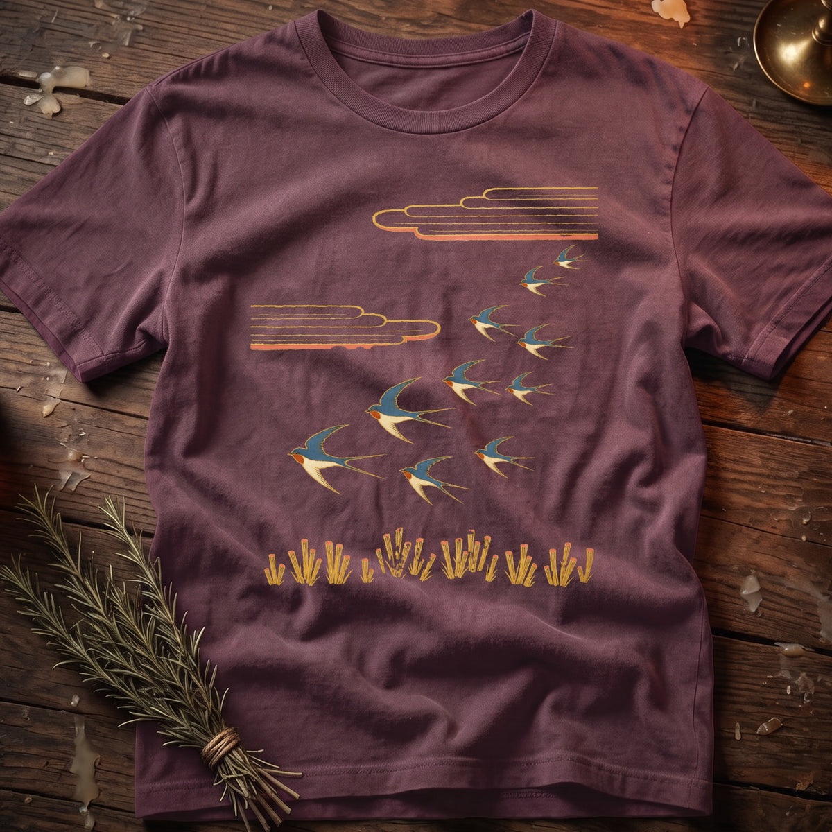 T-shirt with a flock of swallows flying under stylized clouds above reeds.