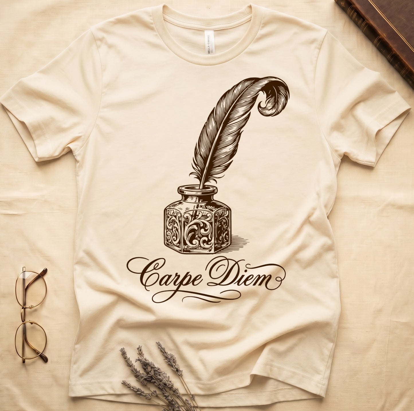 Natural tee with ornate antique inkwell and quill pen in sepia linework, "Carpe Diem" in flowing cursive below.