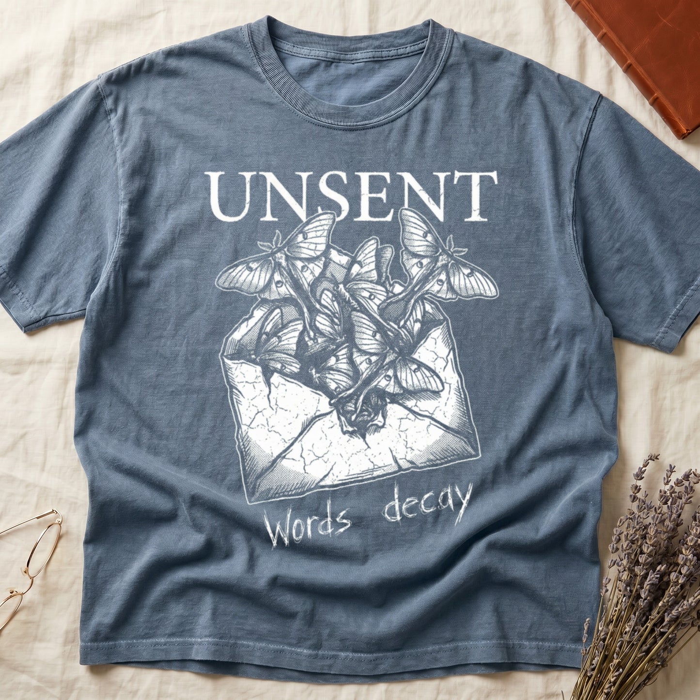 Blue Jean tee with 'UNSENT' in serif type, 'Words decay' brush text, luna moths from torn envelope in crosshatched ink