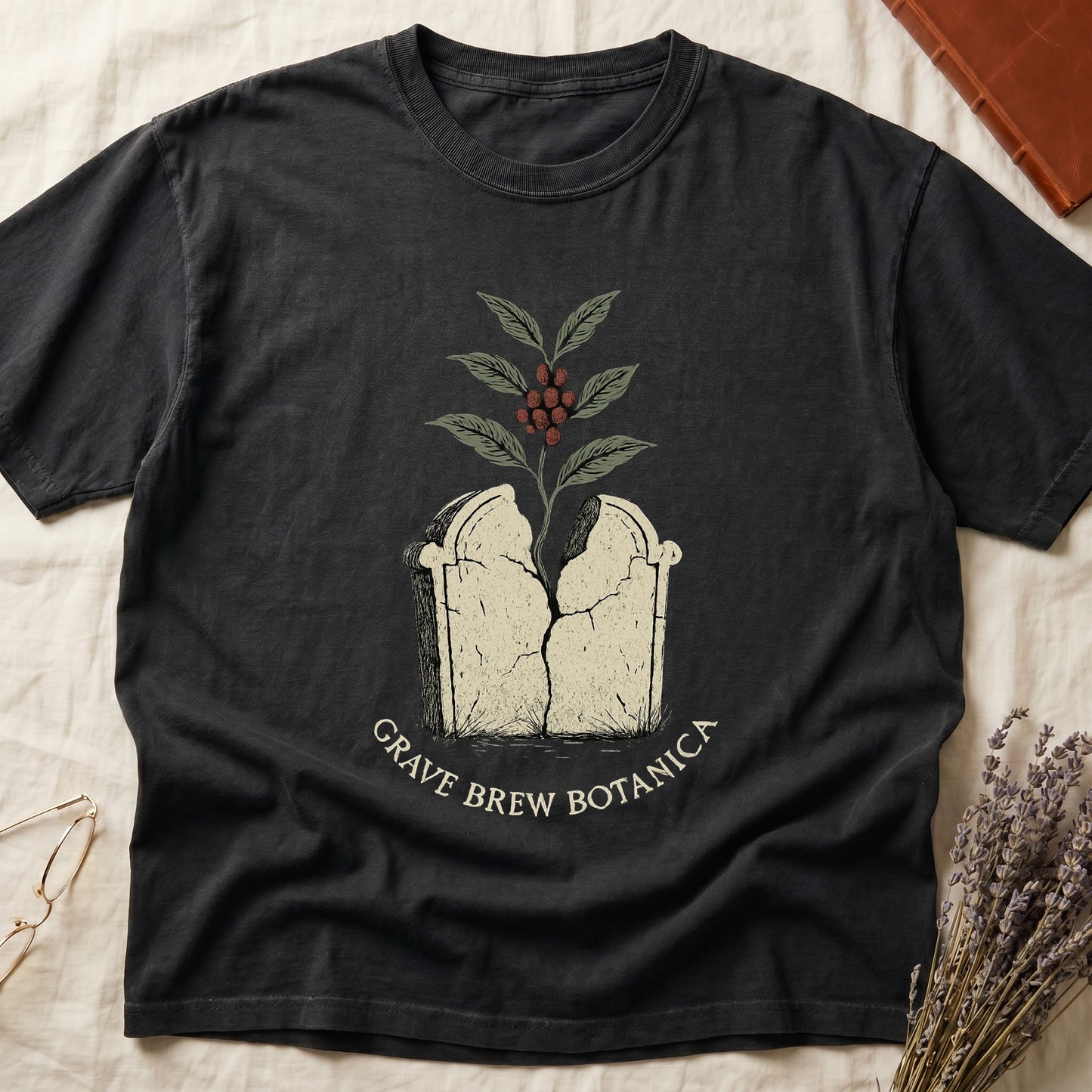 Dark t-shirt with cracked tombstone design and coffee plant, text reads Grave Brew Botanica.