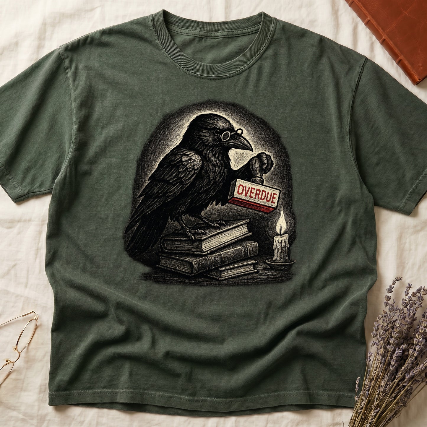 Green tee with bespectacled raven on stacked books, holding wooden "OVERDUE" stamp, lit candle beside, dawn glow behind.
