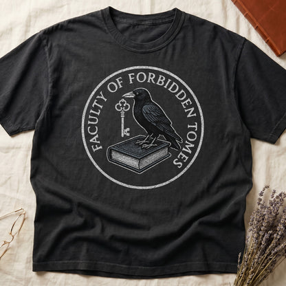 Pepper tee with circular badge, raven on closed book holding key, "FACULTY OF FORBIDDEN TOMES" curved around in cream.