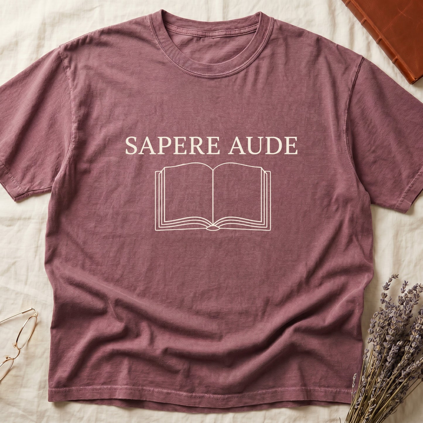 Dark Rose tee with "SAPERE AUDE" in serif capitals above a minimalist open book in cream linework.