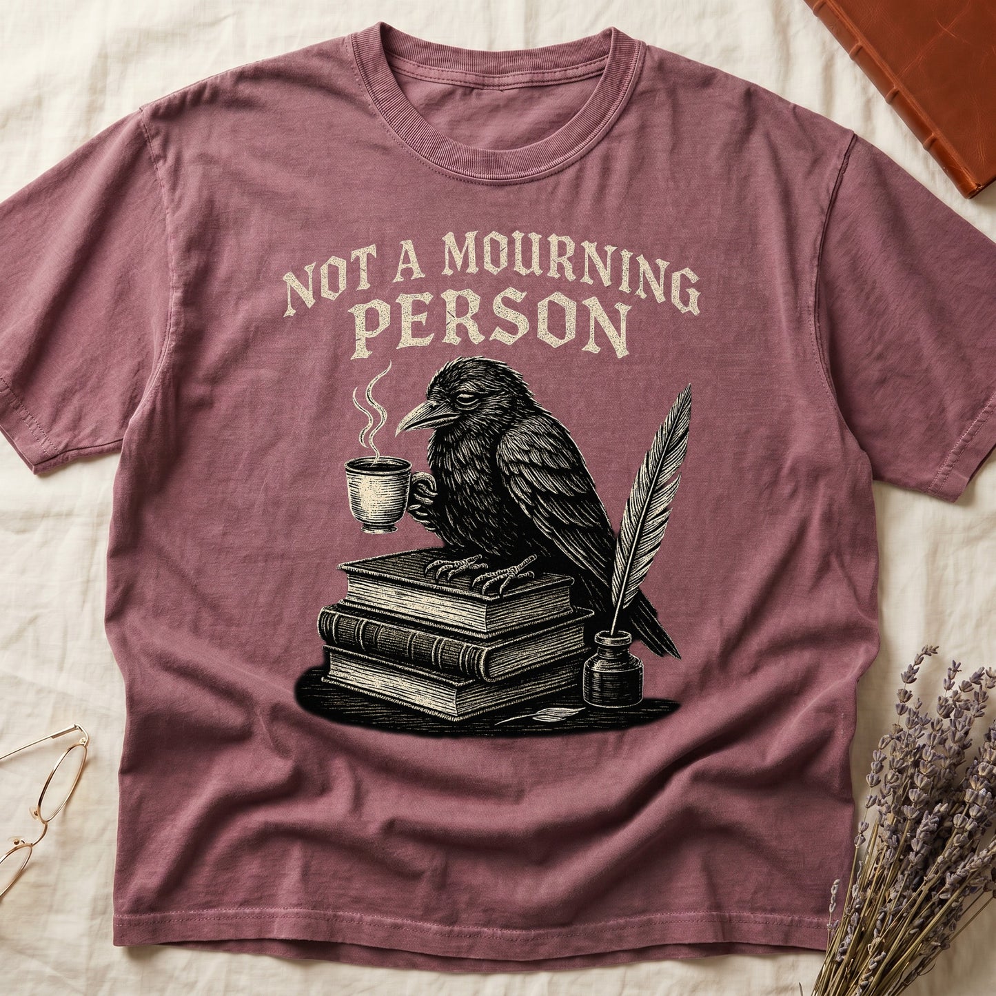 Blue Jean tee with raven holding coffee on stack of books, quill in inkwell, "NOT A MOURNING PERSON" distressed serif top.