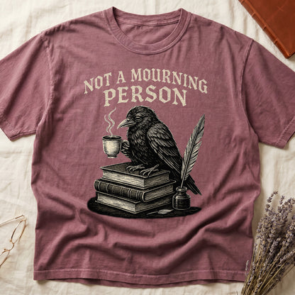 Blue Jean tee with raven holding coffee on stack of books, quill in inkwell, "NOT A MOURNING PERSON" distressed serif top.