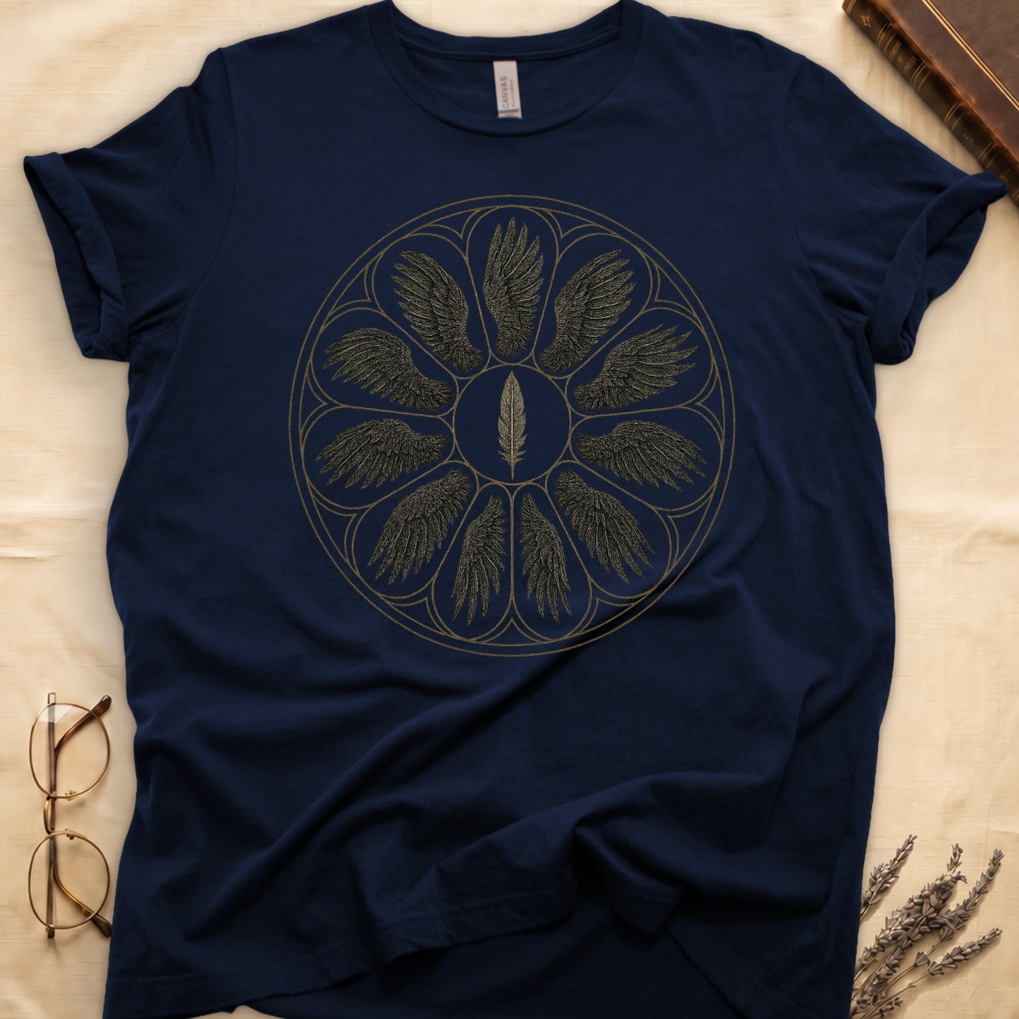 Navy tee with sepia rose-window of eight feathered wings around central feather, engraved linework on parchment ground.