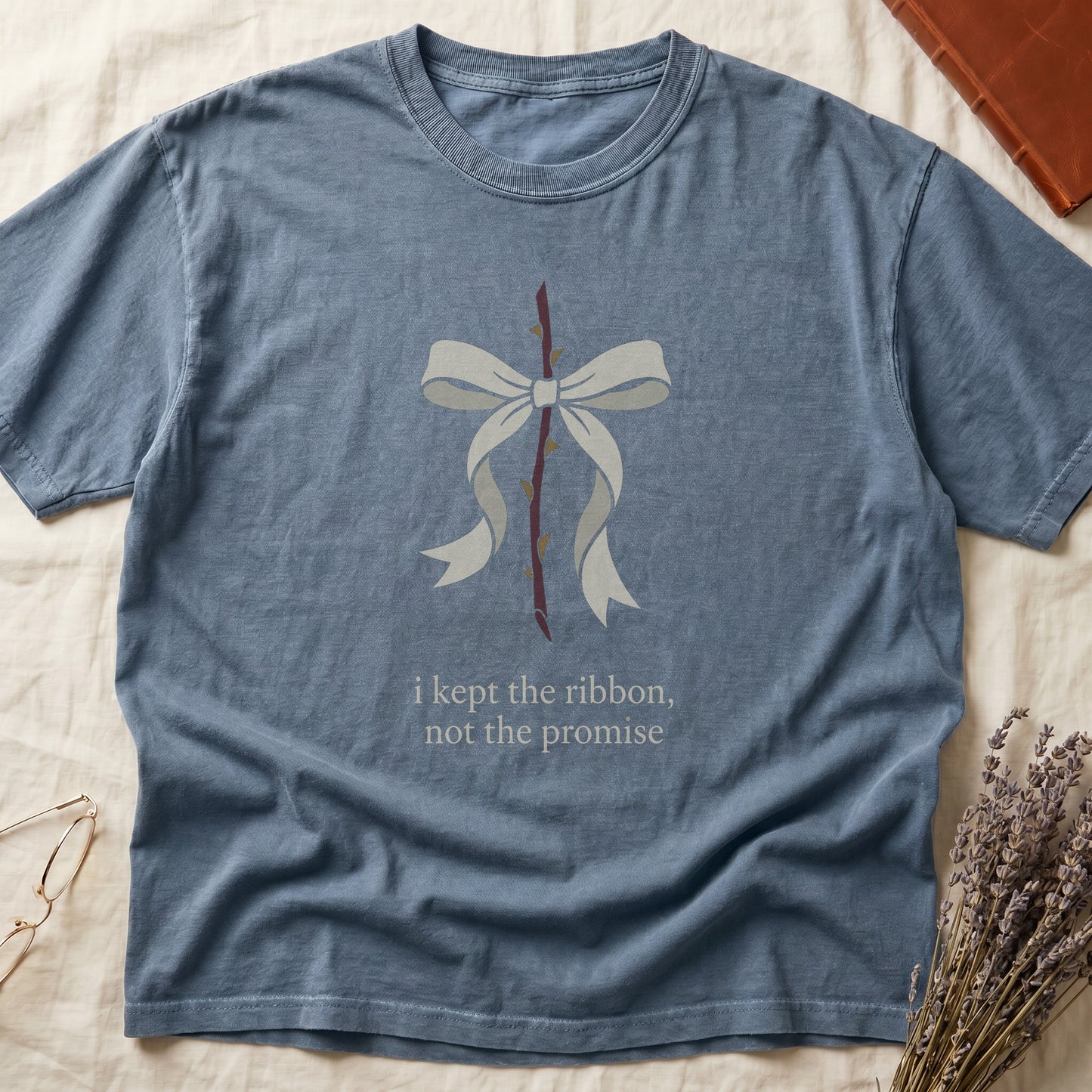Blue Jean tee with cream bow tied around thorny rose stem, "i kept the ribbon, not the promise" in cream serif below.