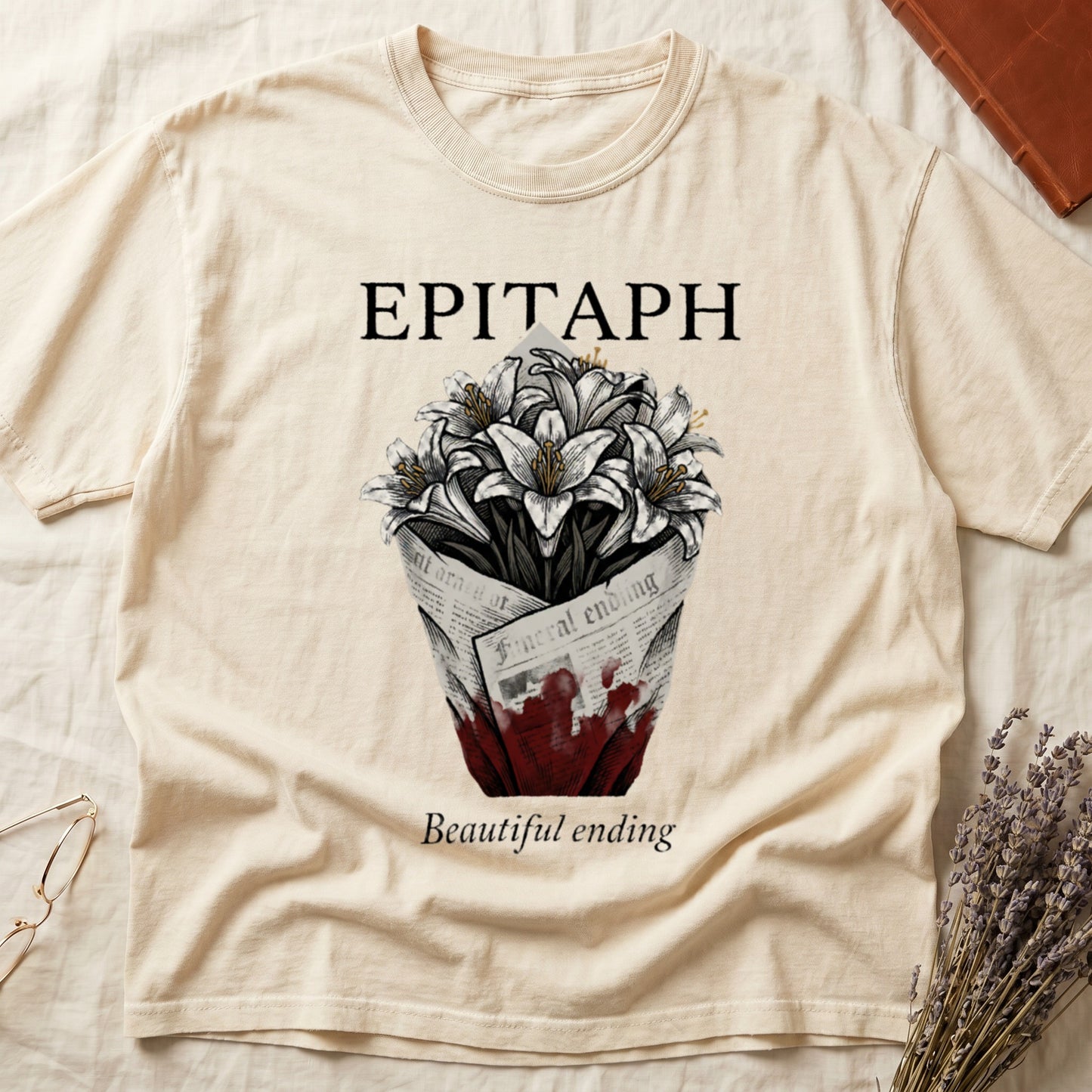 Ivory tee with "EPITAPH" over crosshatched white lilies in blood-stained newsprint wrap, "Beautiful ending" italic serif.