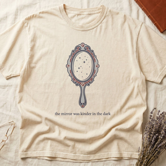 Ivory tee with ornate hand mirror, dark red roses, starfield reflection, "the mirror was kinder in the dark" serif below.