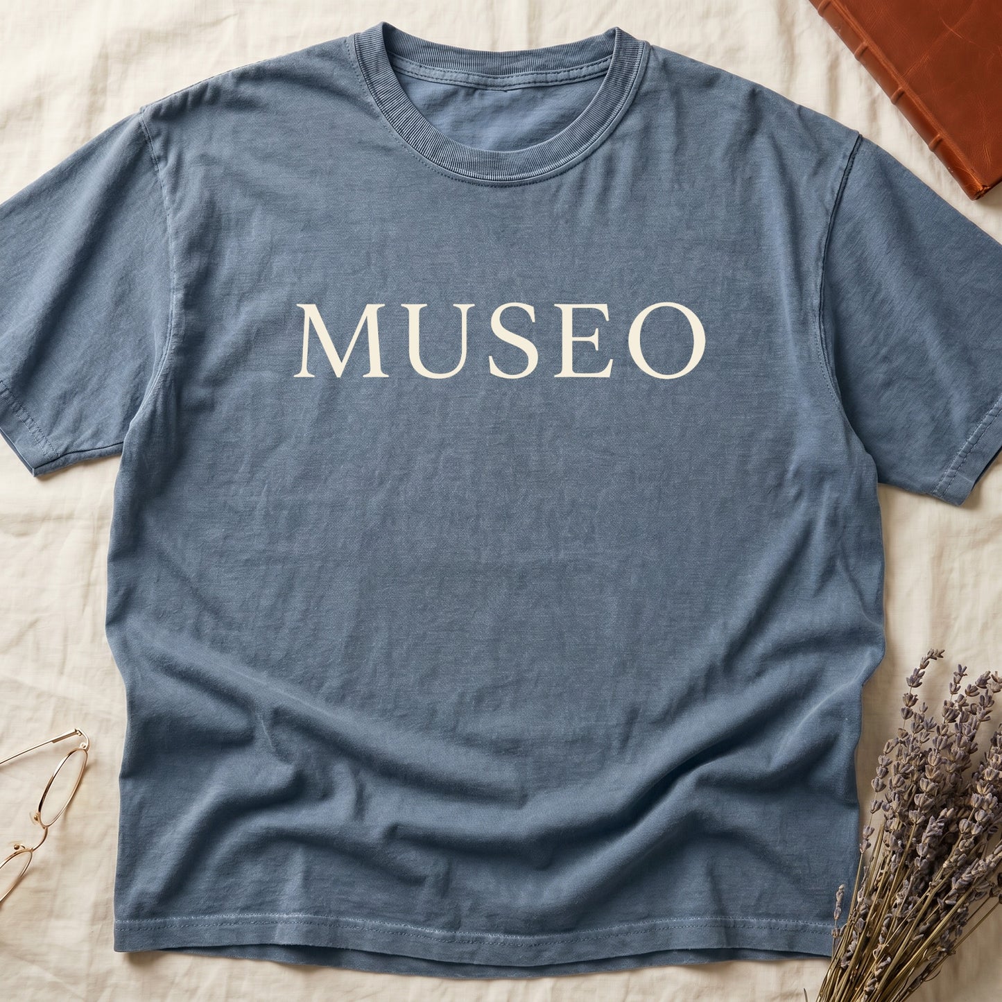 Blue Jean tee with "MUSEO" in oversized cream serif capitals, minimalist typographic design.