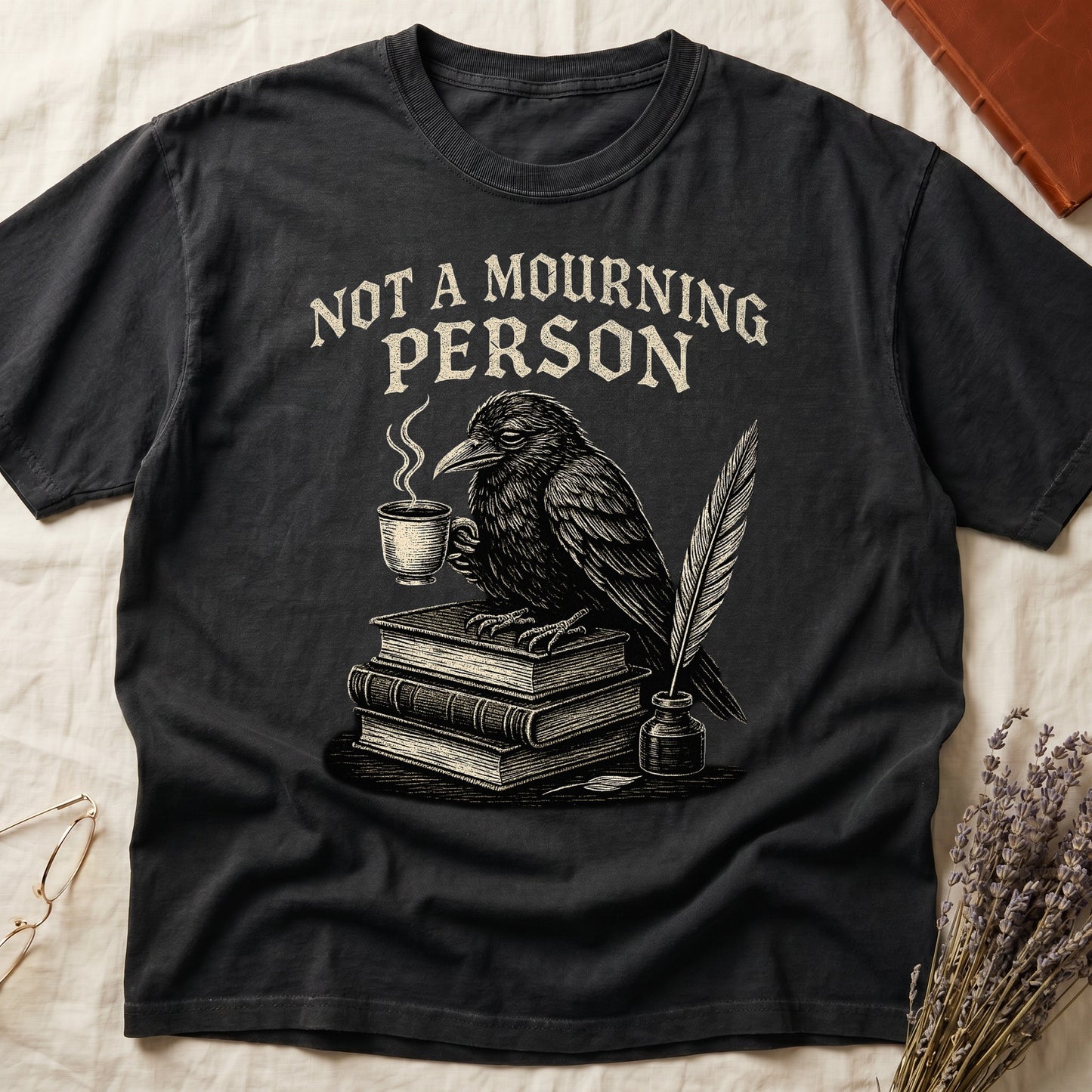 Pepper tee with raven holding coffee on stack of books, quill in inkwell, "NOT A MOURNING PERSON" distressed serif top.