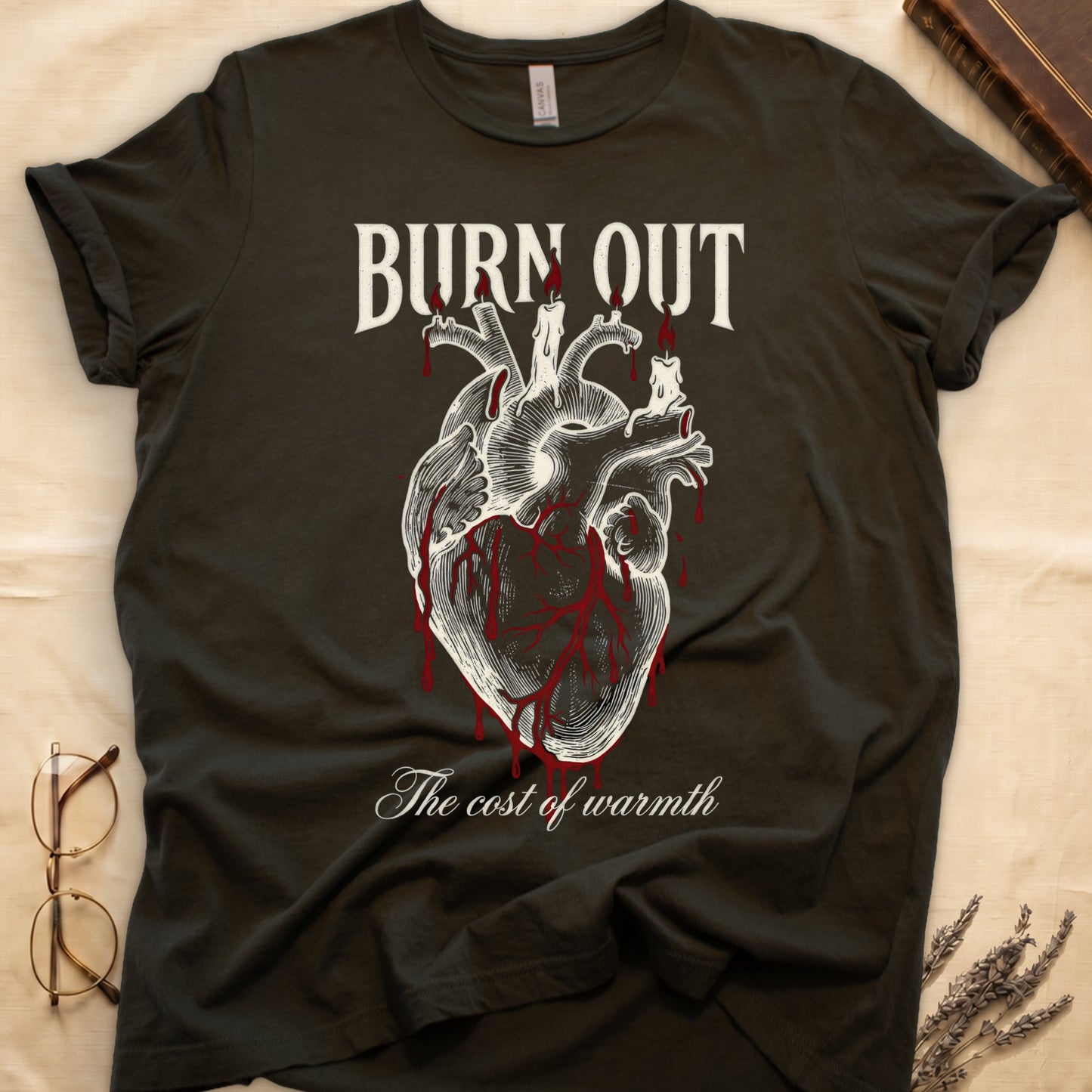 Military Green tee with anatomical heart and melted candles dripping red wax, "BURN OUT" top, "The cost of warmth" cursive below.