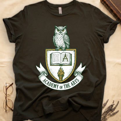 Military Green tee with heraldic shield crest, owl perched on top, open book and dividers center, "ACADEMY OF THE ARTS" on a banner.