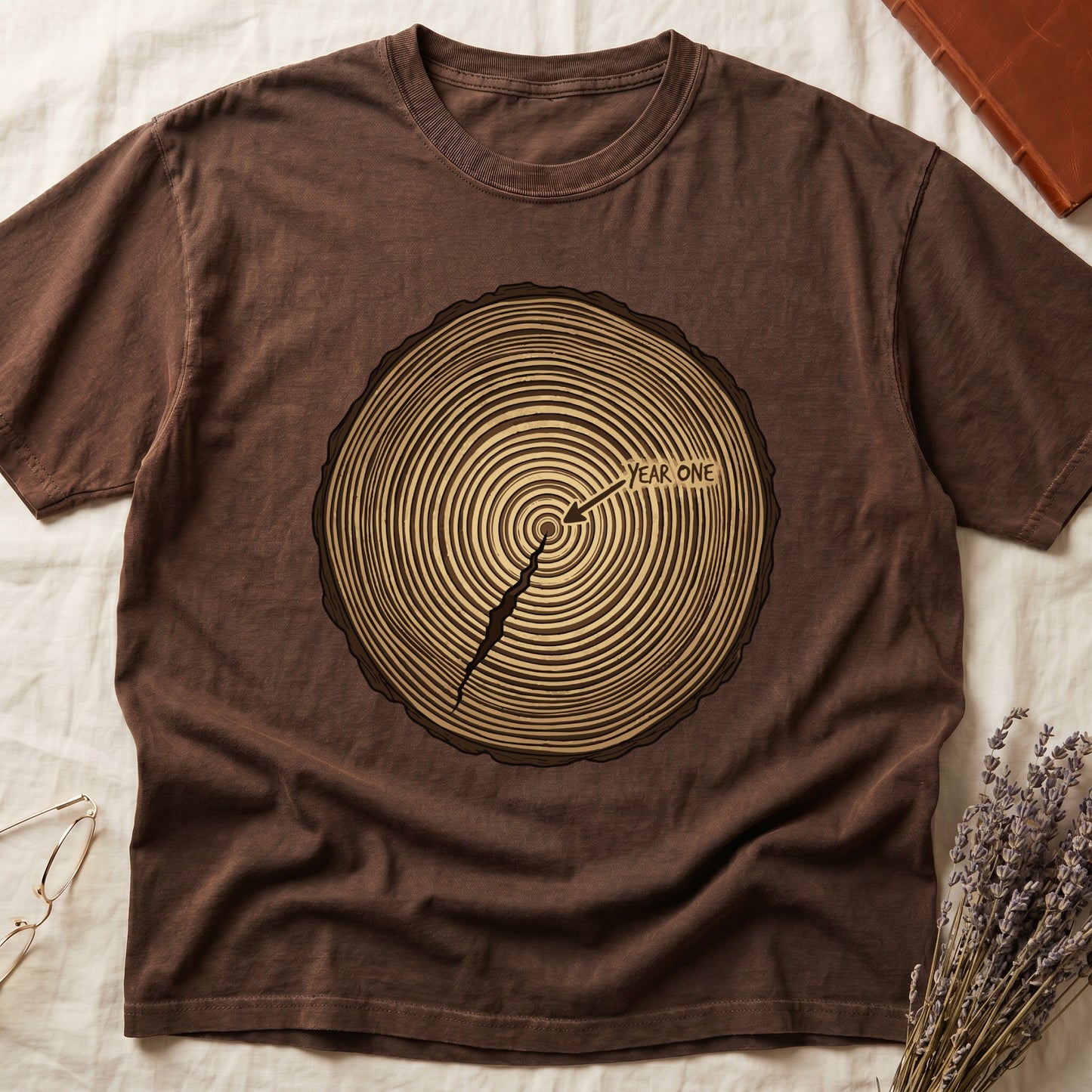 Espresso tee with cross-section of tree rings in warm brown, arrow pointing to center labeled "YEAR ONE" in serif type.