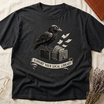 Pepper tee with raven writing on "823.4" parchment by candlelight, ink jar beside, "MIDNIGHT CATALOGUER" banner above.