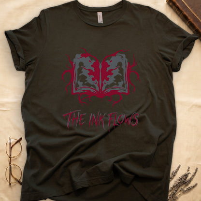 Military Green tee with open book bleeding red ink into a gray face on green ground, "THE INK FLOWS" in dripping serif.