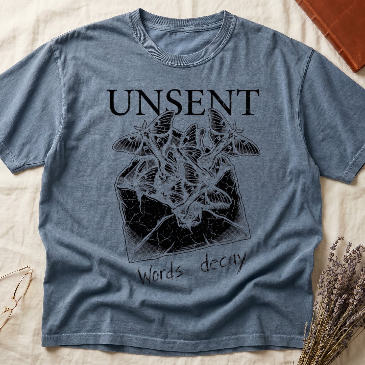 Blue Jean tee with 'UNSENT' in serif type, 'Words decay' brush text, luna moths from torn envelope in crosshatched ink