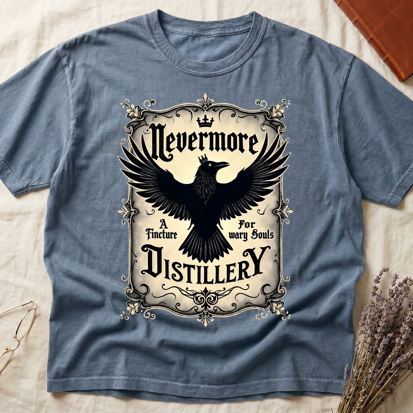 Blue Jean tee with antique label, crowned raven, blackletter "Nevermore" top, "A Tincture For wary Souls," "DISTILLERY" bottom.