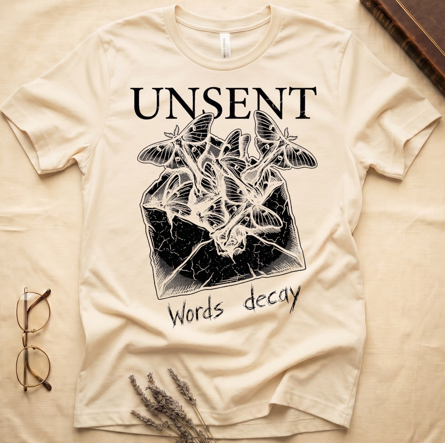 Natural tee with 'UNSENT' in serif type, 'Words decay' brush text, luna moths from torn envelope in crosshatched ink