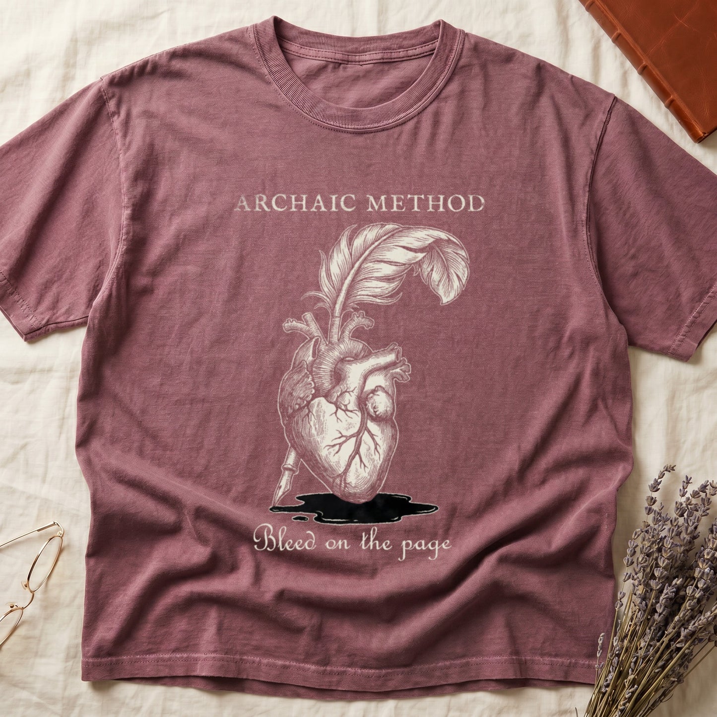 Dark Rose tee with anatomical heart and quill emerging in cream linework, "ARCHAIC METHOD" top, "Bleed on the page" below.