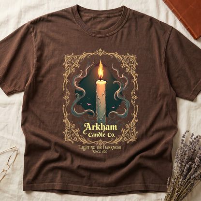Espresso tee with lit candle, smoke, ornate gold filigree border, "Arkham Candle Co.," "Lighting the Darkness Since 1920."