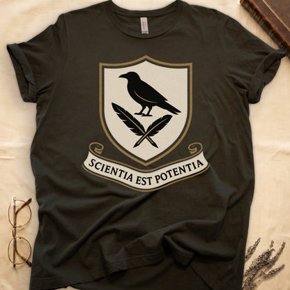 Military Green tee with cream-and-gold heraldic shield, black raven over crossed quills, scroll banner "SCIENTIA EST POTENTIA" below.