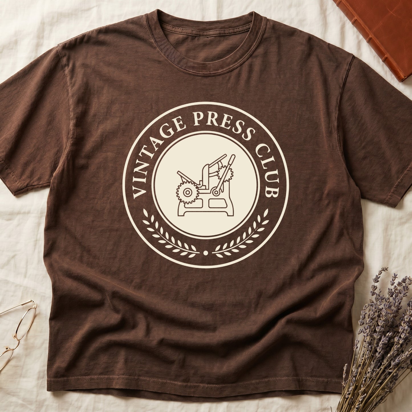 Espresso tee with circular letterpress badge, "VINTAGE PRESS CLUB" in serif capitals, antique printing press in cream linework.