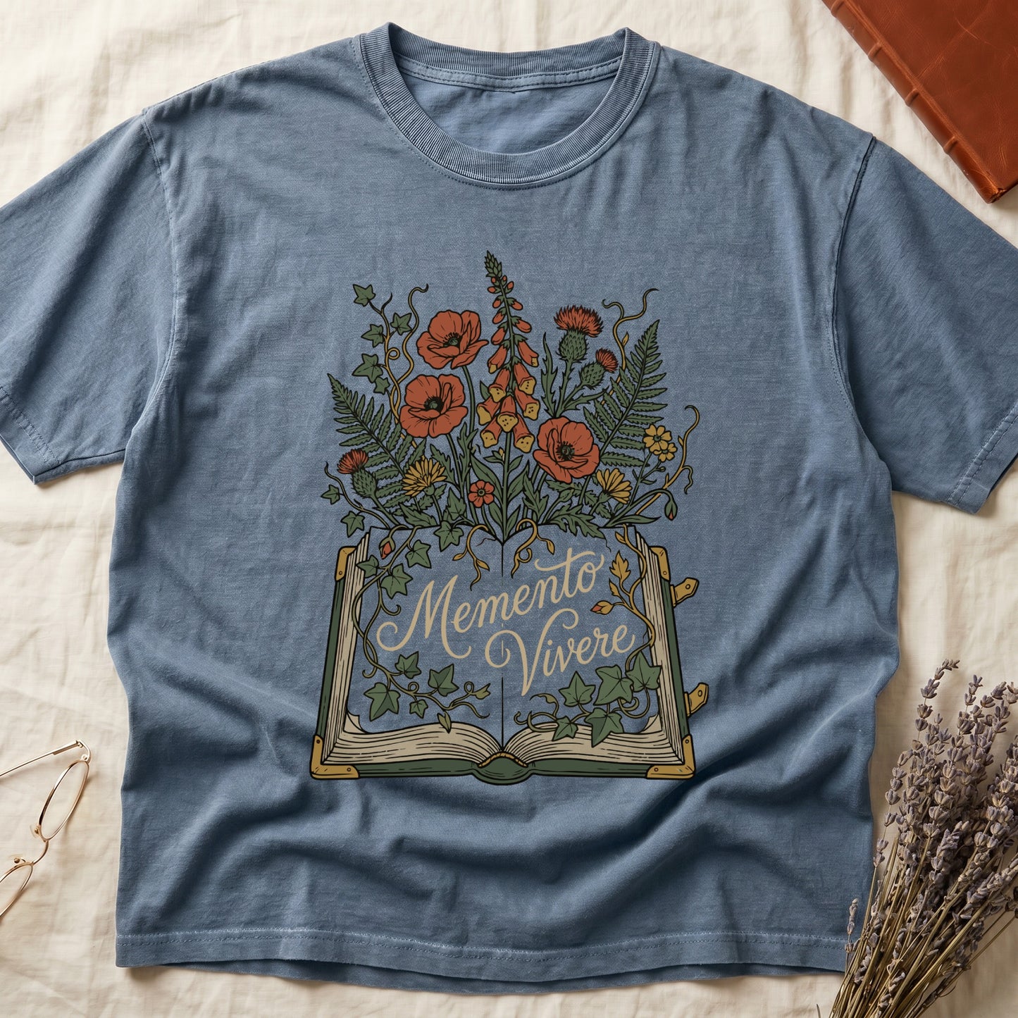 Blue Jean tee with open book and botanical illustration, red poppies, golden foxglove, ferns and ivy spilling from the pages.