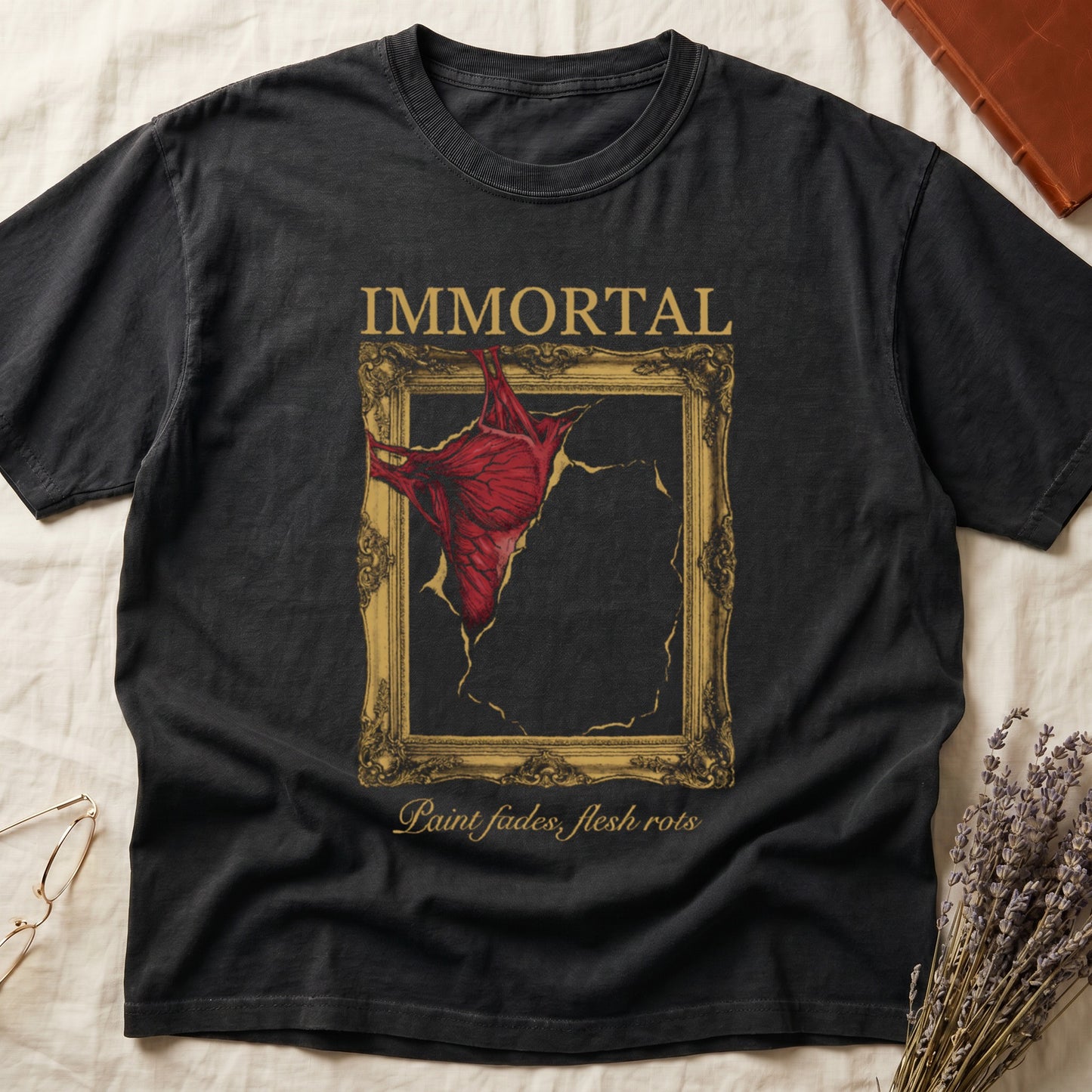 Black tee with gold frame and exposed muscle tearing canvas, "IMMORTAL" top, "Paint fades, flesh rots" italic below.