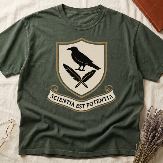 Green tee with cream-and-gold heraldic shield, black raven over crossed quills, scroll banner "SCIENTIA EST POTENTIA" below.