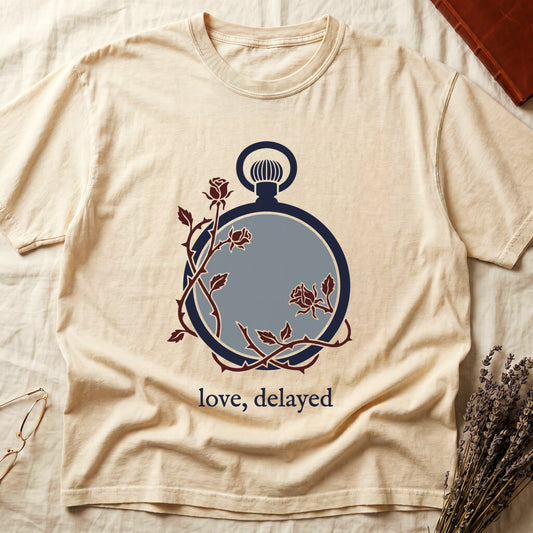 Ivory tee with vintage cream pocket watch and dark red roses entwined, "love, delayed" in cream serif below.