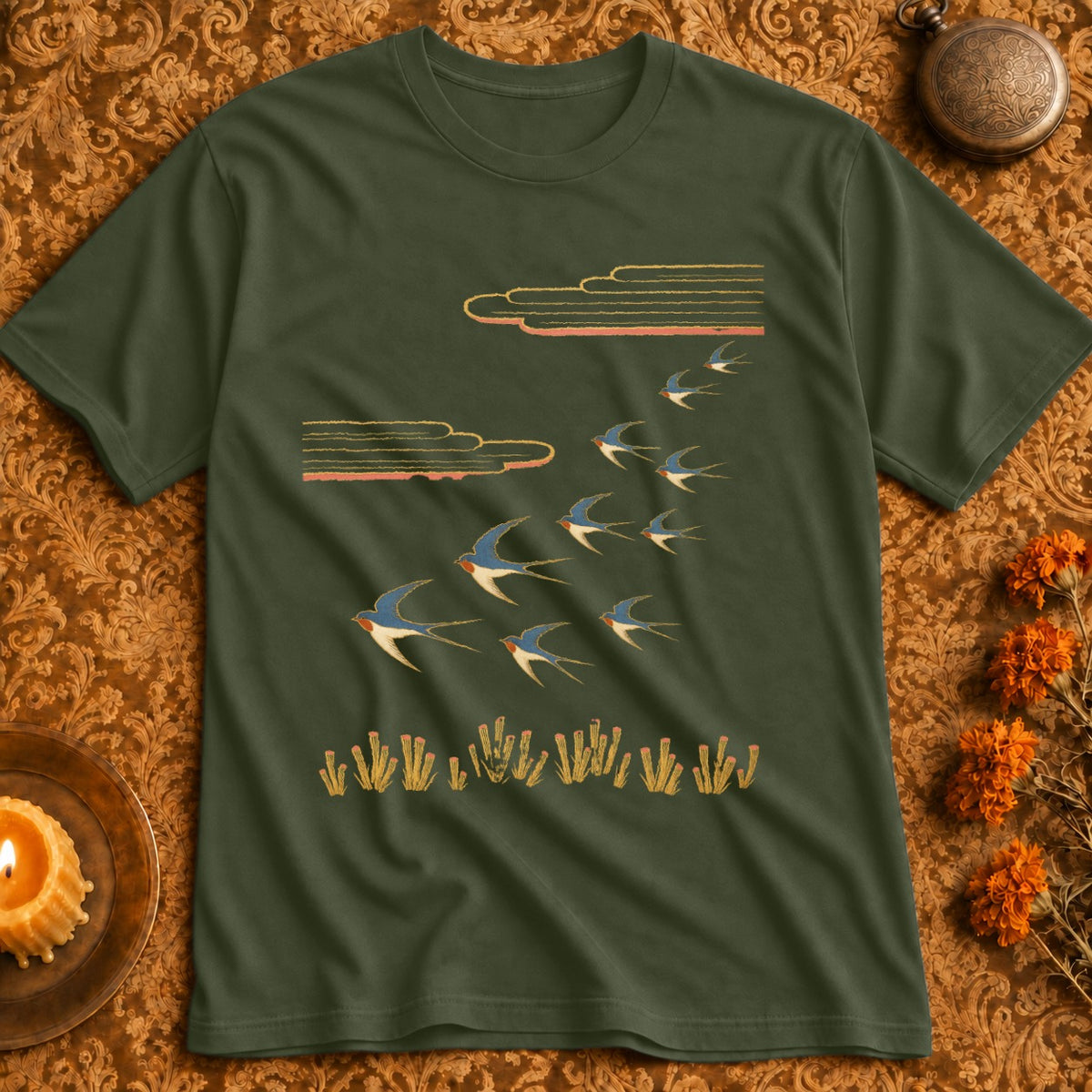Green t-shirt with a flock of blue and white swallows flying past stylized clouds and reeds.