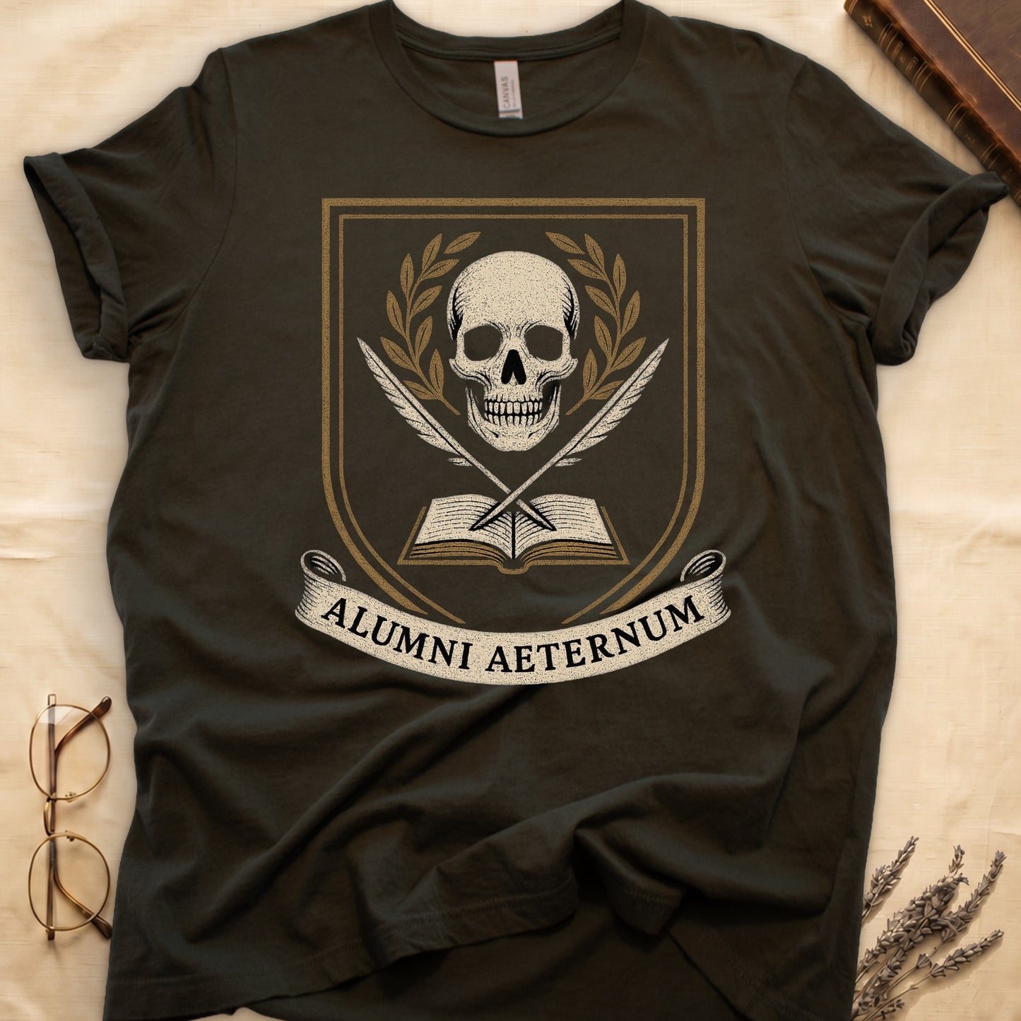 Military Green tee with heraldic shield, skull and gold laurels, crossed quills, open book, scroll "ALUMNI AETERNUM" below.