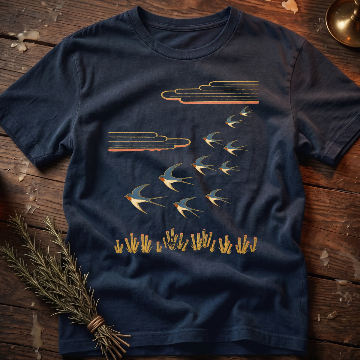 Navy t-shirt with a flock of swallows and stylized clouds above grass.