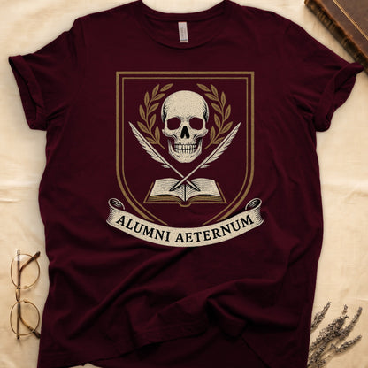 Maroon tee with heraldic shield, skull and gold laurels, crossed quills, open book, scroll "ALUMNI AETERNUM" below.
