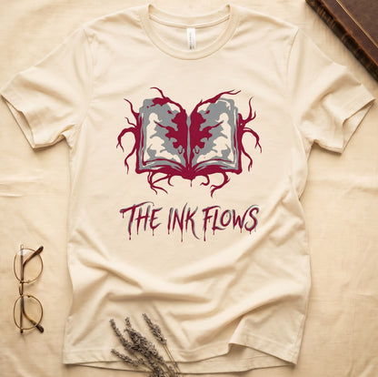 Natural tee with open book bleeding red ink into a gray face on green ground, "THE INK FLOWS" in dripping serif.