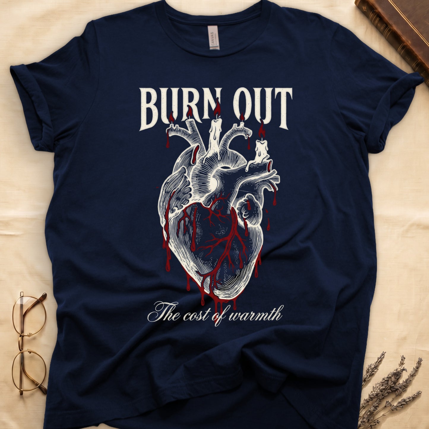 Navy tee with anatomical heart and melted candles dripping red wax, "BURN OUT" top, "The cost of warmth" cursive below.
