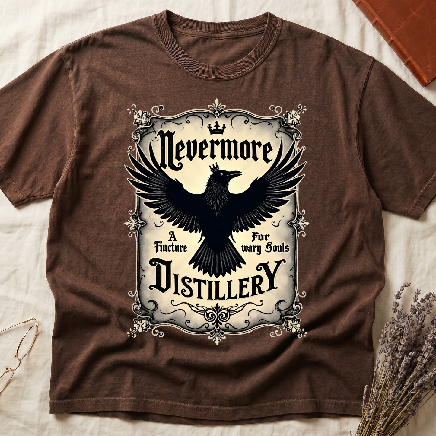 Espresso tee with antique label, crowned raven, blackletter "Nevermore" top, "A Tincture For wary Souls," "DISTILLERY" bottom.