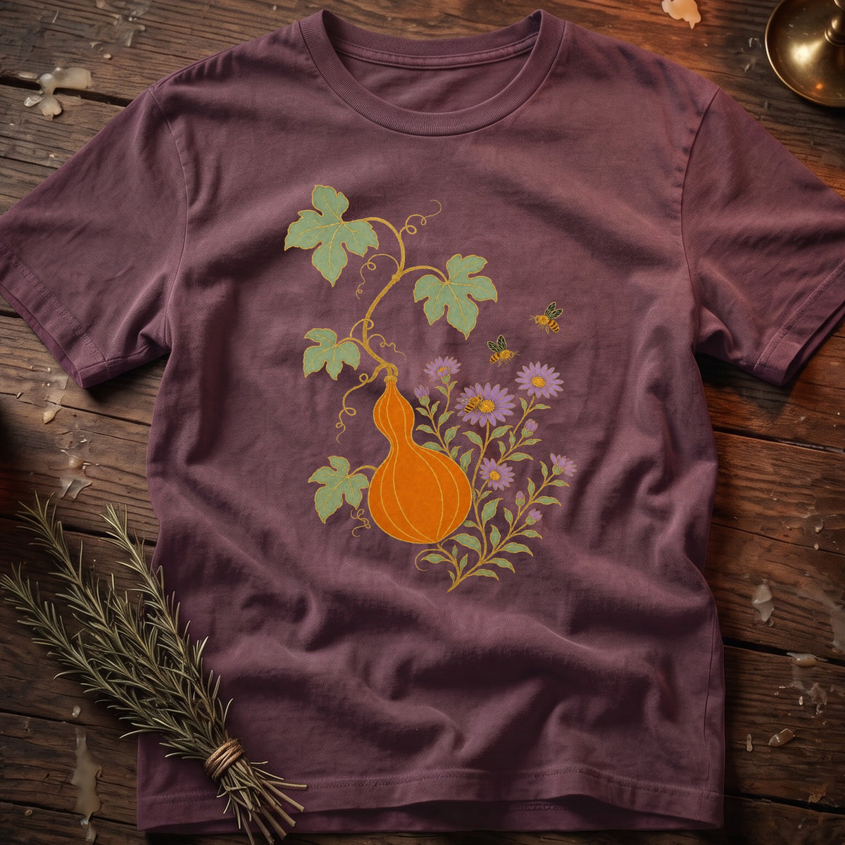 Burgundy t-shirt with orange gourd, flowers, leaves, and bees graphic.