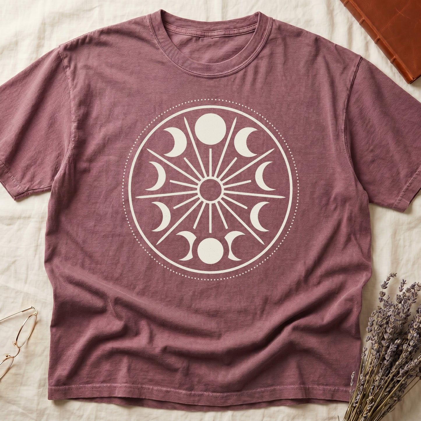 Dark Rose tee with cream lunar orrery wheel, dotted ring, radial sunburst, moon phases around perimeter, central star.