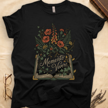 Black tee with open book and botanical illustration, red poppies, golden foxglove, ferns and ivy spilling from the pages.