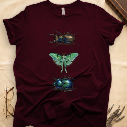 Black tee with three-panel Maroon-history plate: stag beetle, luna moth, scarab beetle in ink on yellow ground.