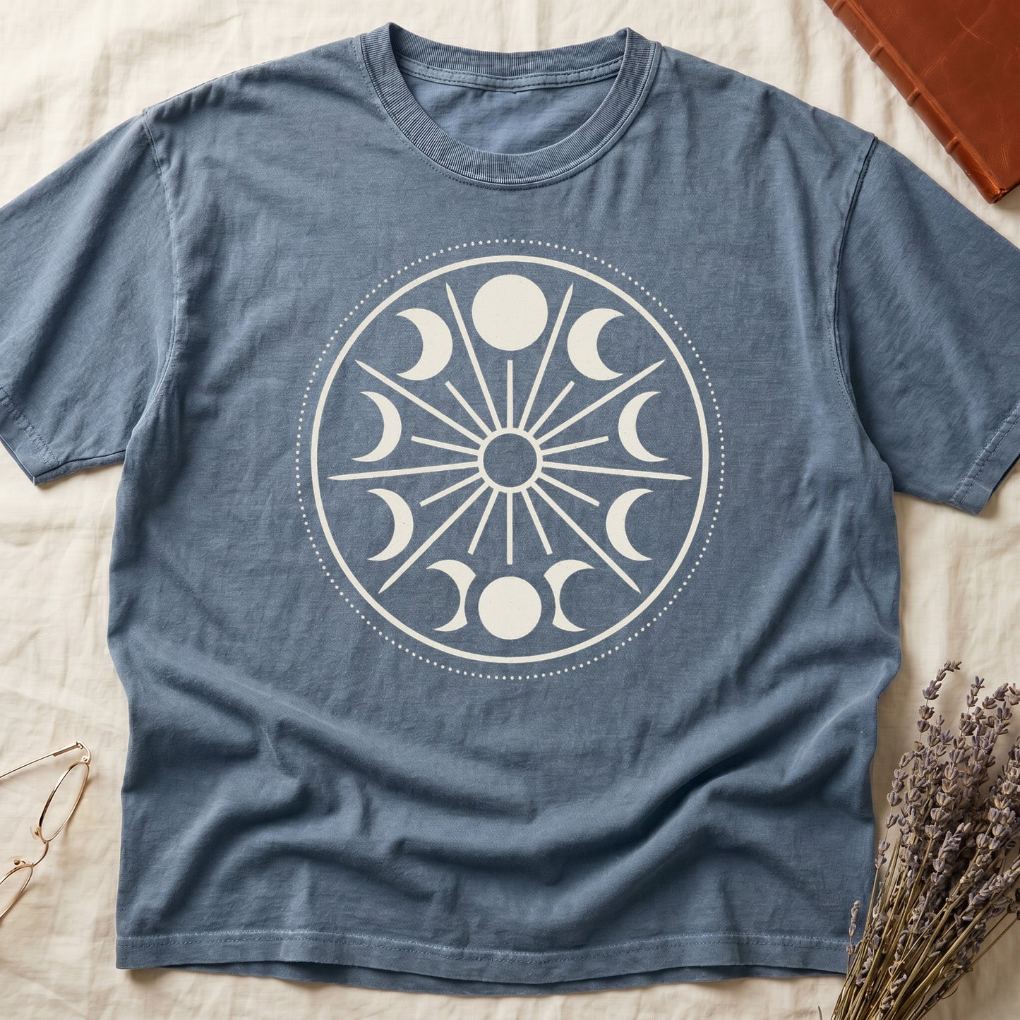 Blue Jean tee with cream lunar orrery wheel, dotted ring, radial sunburst, moon phases around perimeter, central star.