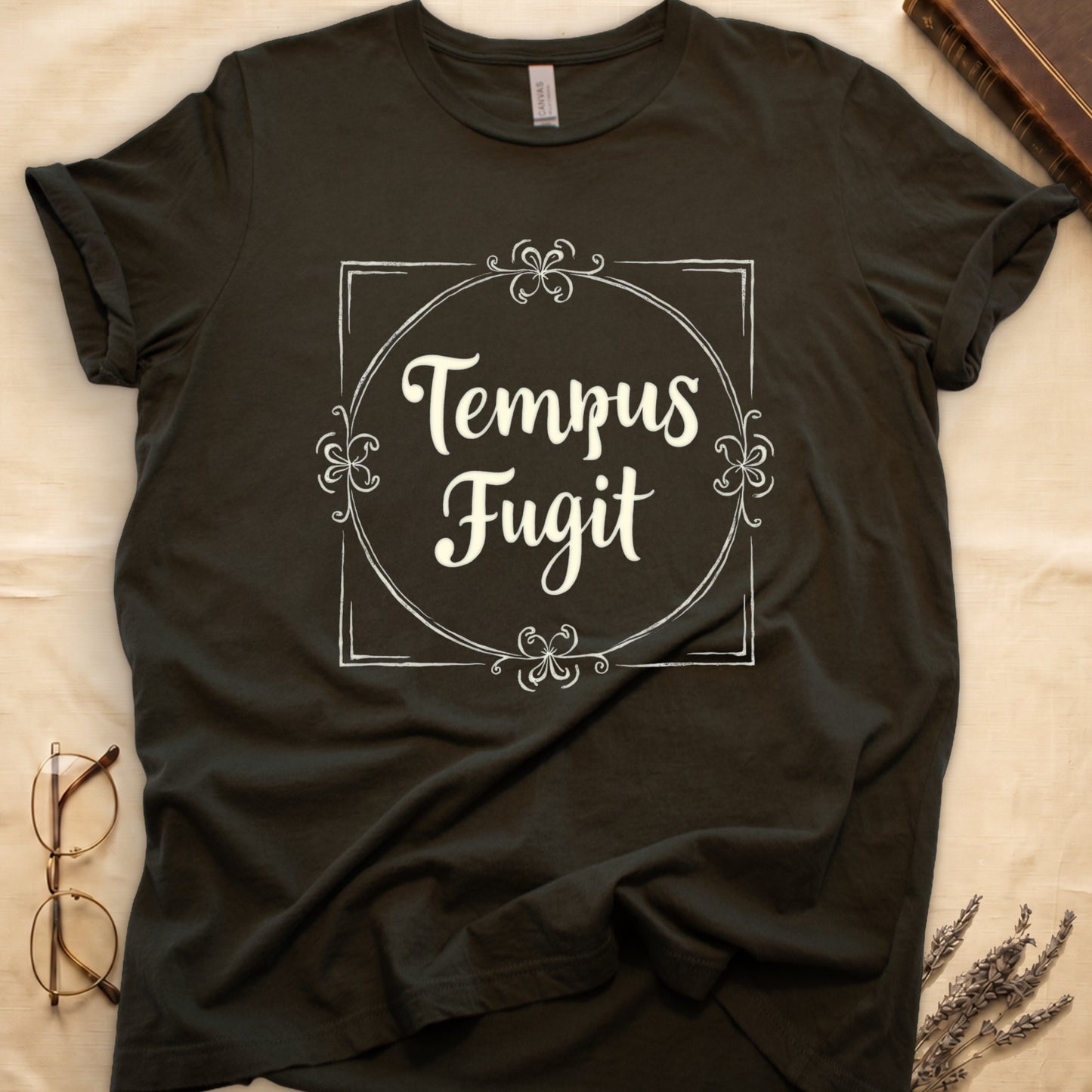 Military Green tee with cream "Tempus Fugit" script inside square filigree frame, decorative corner flourishes, classical typography.