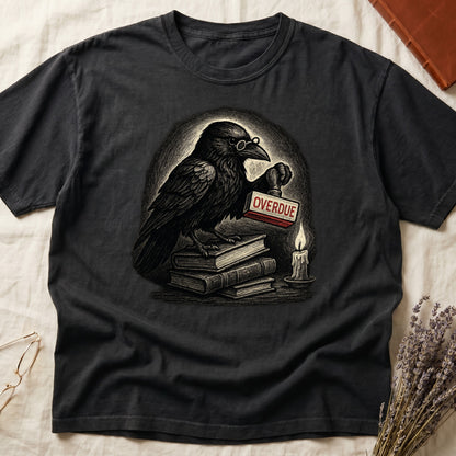 Black tee with bespectacled raven on stacked books, holding wooden "OVERDUE" stamp, lit candle beside, dawn glow behind.