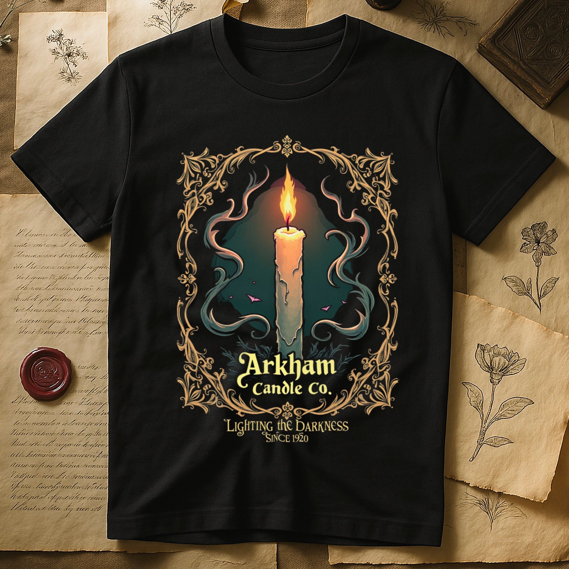 Black tee with lit candle, smoke, ornate gold filigree border, "Arkham Candle Co.," "Lighting the Darkness Since 1920."