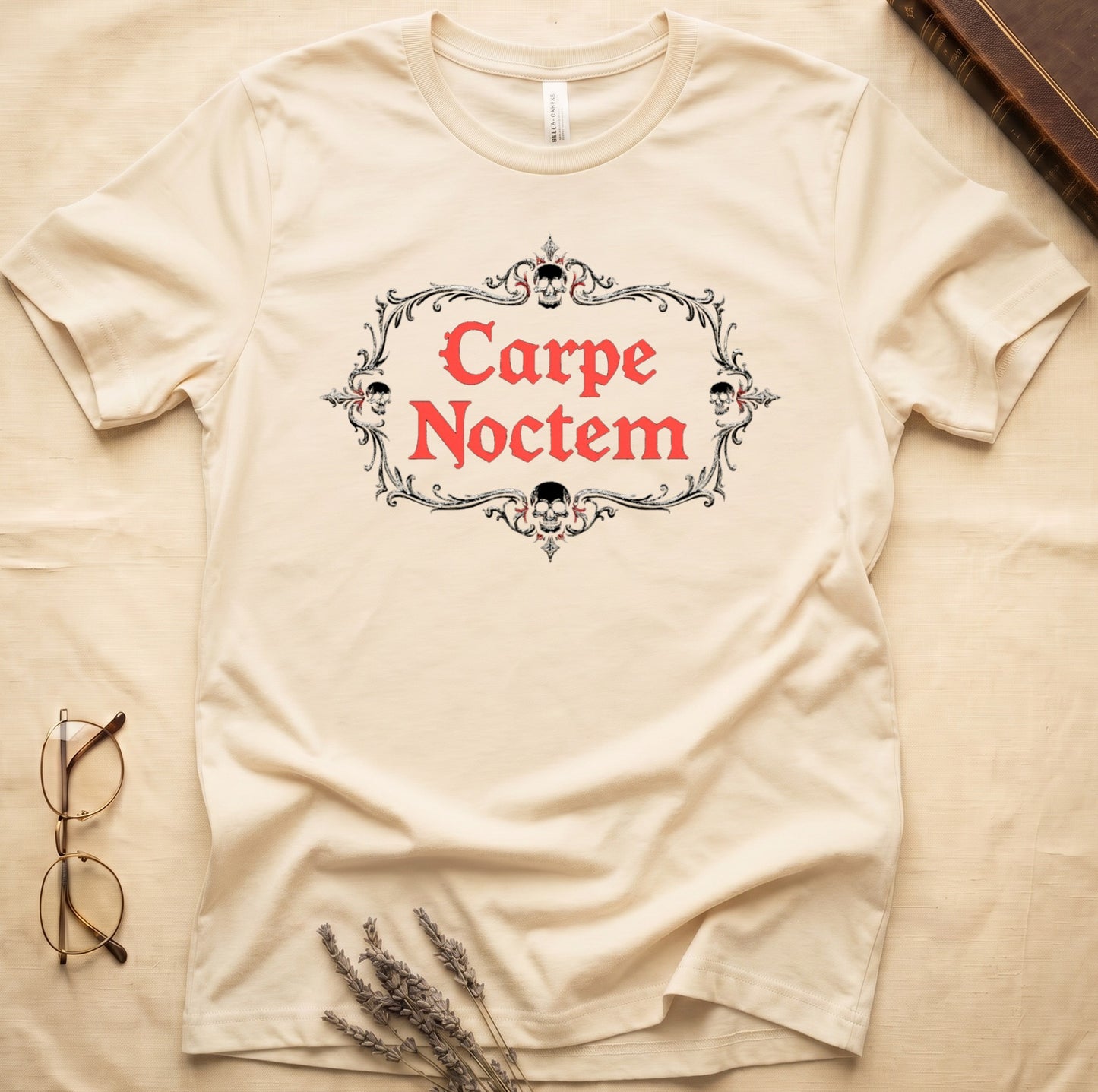 Natural tee with silver filigree cartouche, crowned skull top and skull below, "Carpe Noctem" in deep-red blackletter inside.